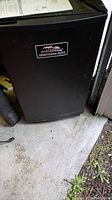 Front black exterior view of tall rectangular electric smoker with Masterbuilt Sportsman Elite badge visible.