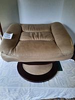 Top view of beige leather cushion showing plush padding and stitch details and swivel ottoman base