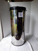 Front view showing full height and reflective stainless steel surface with black lid