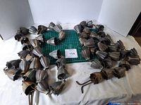 Two metal cup rain chains laid flat showing the full length and shape of the connected cups, on a white background with measurement grid underneath to indicate size.