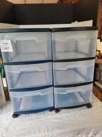 Front view of two Sterilite 3-drawer storage units side by side, showing translucent drawers and black and blue frames on caster wheels.