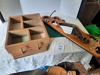 Side view of two wooden wall display units on a white surface, showing cubby organizer and wooden/glass hanger with brass pegs