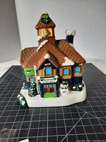 Front view of Seahawks Christmas Village School House showing sign, snowman, and snow-covered roof with Seahawks logo on clock tower.