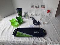 Full view of Seattle Seahawks serving tray, green condiment bowls, tall Rogue Cider glasses, Canadian hockey logo glass, smaller glass, and Seahawks bottle opener.