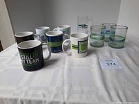 Photo of 10 Seahawks-themed drinkware items including 7 ceramic mugs and 3 glasses with team logos/colors