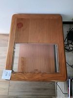 Top-down view of oak end table showing glass inset on top with a visible reddish-brown stain on the glass surface.