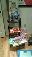 Photo showing various craft and educational toy boxes on a black metal shelf unit, including Primo Cubetto Playset, Klee Kids Sparkle Fairy, and other kits in original packaging.
