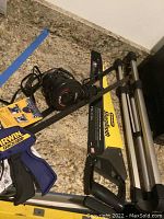 Two Irwin Quick-Grip clamps with packaging, Stanley Sharptooth hand saw, Intex electric air pump and QSX tripod on countertop.