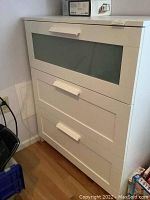 Photo of white dresser with three drawers, top drawer has frosted glass panel, rectangular handles.