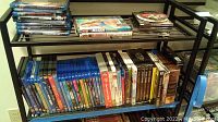 Shelf with stacks of DVDs and Blu-rays, showing different movies including Star Wars box sets and various Disney titles.