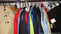 Clothing rack with two kilts and multiple short-sleeve men's shirts hung on hangers