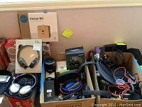 Collection of various headphones, AIY Vision Kit box, Bluetooth speaker and other equipment on shelf