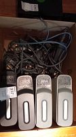 Photo showing four Xbox 360 consoles with hard drives in a box along with a tangle of cables.