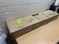 Photo of boxed black metal twin size bed frame showing product label and schematic, with new in box condition indicating unused item.