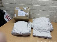 Photo showing new heather grey jersey knit bed sheet set items neatly folded alongside the original box.