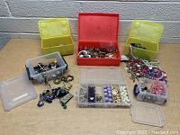 Front view of the lot showing a red container, two yellow containers, and several clear plastic containers filled with various jewelry and beads.