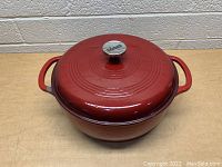 Front view of red enamel Lodge Dutch oven with lid and Lodge branded knob.