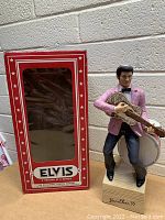 Full view of Elvis Presley whiskey decanter figurine beside original red display box.