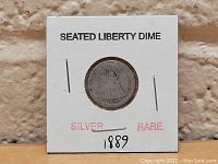 Silver Seated Liberty Dime dated 1889 secured in a white cardboard holder with labels 'SEATED LIBERTY DIME', 'SILVER', 'RARE' and handwritten '1889'.
