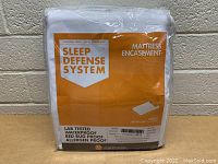 Packaged Sleep Defense System mattress encasement for queen size bed, showing front label with product features and size.