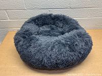 Front angle view of the round gray plush pet bed showing the soft texture and raised sides.
