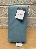 Front view of folded, packaged light blue Threshold king flat sheet with visible tag.