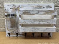 Front view of wall mount key rack with six hooks and mason jar attached on left side.