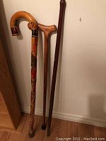 Full view of three wooden canes and walking sticks showing different styles and finishes.