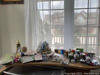 Wide view showing assorted arts and craft supplies on table by window, a variety of bottles, packages, and loose items visible.