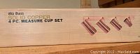 Box front and labeling for Old Dutch 4 pc solid copper measure cup set, showing set of 4 measuring cups illustration and product name.