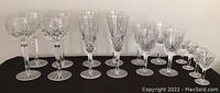 Full set of 16 crystal stemware glasses arranged by size and type on black surface