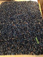 Full view of one rug showing dark blue, light blue, cream, and red multi-colored looped fabric strips creating a thick and textured surface.