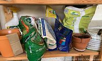 Shelf with various bags of fertilizers, grass seeds, and small plant pots
