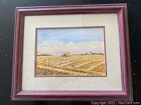 Framed watercolour painting showing rural harvest scene with combine harvester, signed by Phyl Dickie.