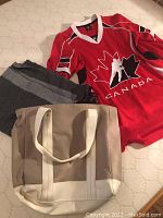 Red Hockey Canada jersey laid out with visible large white and black hockey player logo and red/black/white sleeve stripes.