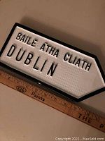Close-up image of Dublin directional sign with embossed lettering in both Irish and English.
