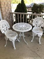 Two white cast metal chairs and round table on patio