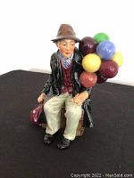 Front side of the Royal Doulton The Balloon Man figurine showing full figure including balloons and seated posture