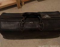 Closed black leather medical bag with handle and zipper