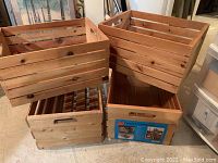Four wooden crates grouped on floor. Two crates have solid sides and two have slatted sides. Natural unfinished wood with visible knots.