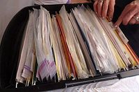 Overhead image showing a file folder densely packed with paper instructions and patterns organized with filing tabs.