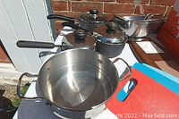 Top view of pots and pans including large stainless steel pot and other medium pots with lids.