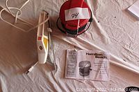 Hamilton Beach breakfast sandwich maker with accompanying manual and electric cutting utensil laid out on a surface.