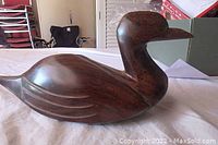 Side view of the carved wooden duck showing the overall shape and finish
