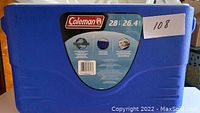 Blue Coleman cooler front label showing brand name, 28 qt / 26.4 litres capacity, and barcode.