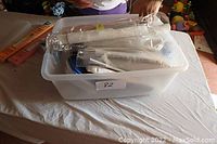 Plastic tote filled with sewing materials and notions showing multiple rolls and packaged items before unpacking