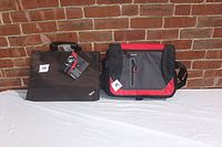 Photo of two new computer carrying cases, one black with ThinkPad logo and one red and grey messenger style, displayed against a brick wall.
