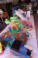 Photo showing assortment of children's toys including push toy, treehouse playset, colorful toys on a table