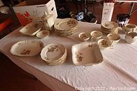 Full display of all dishes including platters, teapot, plates, cream and sugar, and teacups set out on table