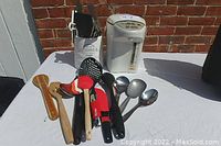 Panasonic electric thermal pot and kitchen utensils arranged on a white cloth with a brick background.